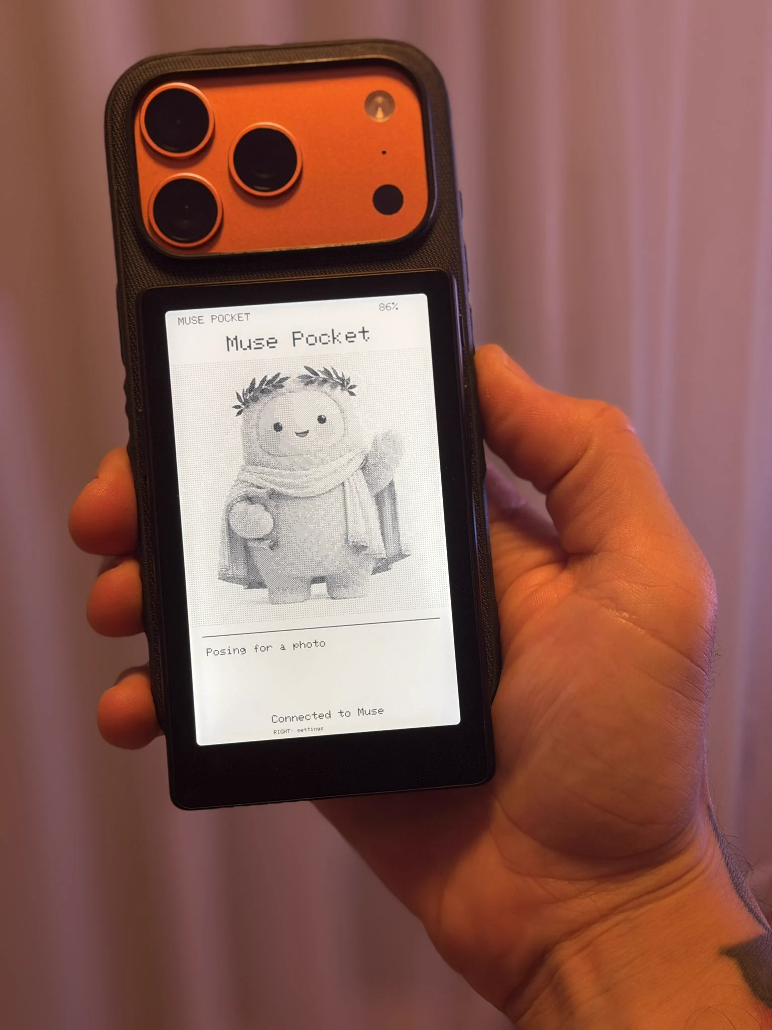 The e-reader attached to the back of a phone with MagSafe, showing Muse's status